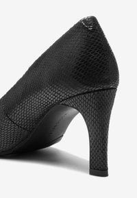Must musta kingad tekstuurse kunstnahast nahaga. Terav varvas, kaarjas siluett ja kitsas stilettokand. Peen brändimine talla peal.