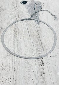 Collana metallica argentata con un design a spirale, caratterizzata da una superficie liscia e un gancio regolabile per variazioni di dimensione.