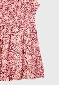 Robe rose avec un corsage froncé et un ourlet à volants, arborant un motif géométrique en rose foncé avec des accents beige partout.