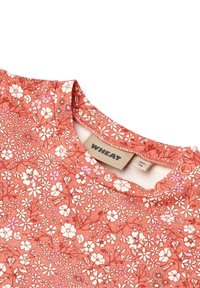 Prim-plan al gulerului unei haine pentru bebeluși cu model floral corai, cu nasture capsa și etichetă de brand "WHEAT" mărimea 9L/74.
