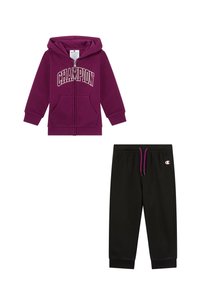 Felpa con cappuccio viola con testo "CHAMPION" e tasche anteriori; abbinata a pantaloni della tuta neri con vita elastica e dettaglio logo.