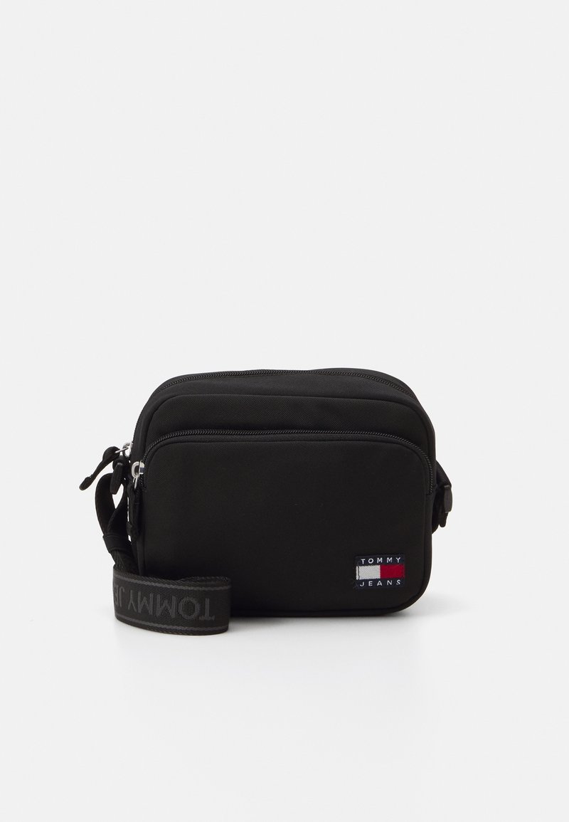 Borsa nera in nylon con due scomparti con cerniera, tracolla regolabile e una piccola etichetta del logo Tommy Jeans con accenti rosso, bianco e blu.