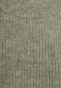 Gros plan sur un tissu tricoté vert olive avec une texture côtelée épaisse et des fibres de fil visibles.