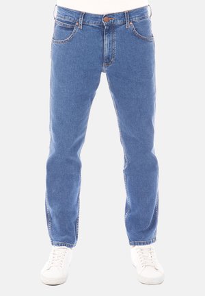 Vaqueros de mezclilla azul con diseño de pierna recta, estilo de cinco bolsillos y costuras visibles. Combinados con zapatillas blancas para un look casual.