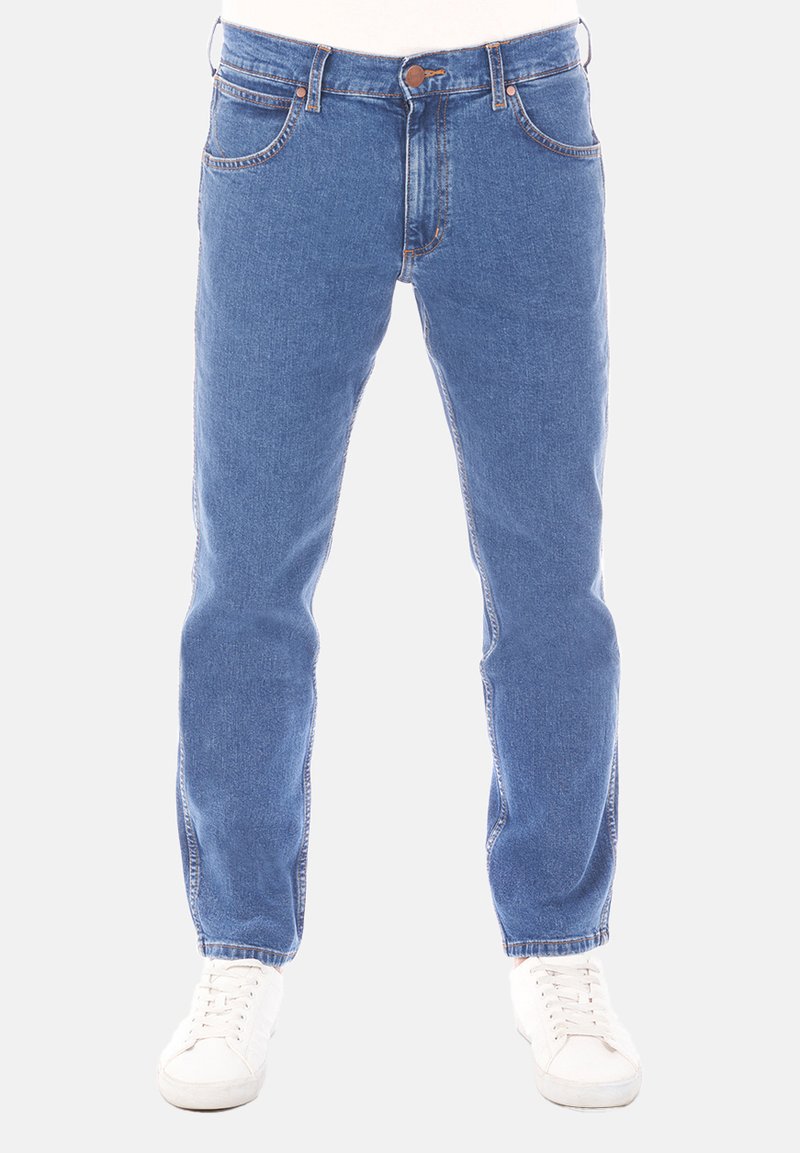 Niebieskie dżinsy z prostą nogawką, w stylu z pięcioma kieszeniami, z widocznym przeszyciem. Połączone z białymi trampkami dla codziennego wyglądu.