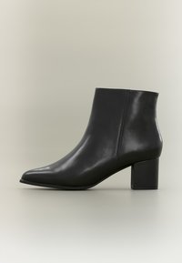 Stivali alla caviglia neri in pelle liscia con punta affusolata e tacco quadrato robusto. Il design è elegante e dallo stile minimalista.