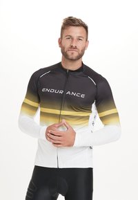 Langarm-Radtrikot mit einem Farbverlauf von Schwarz zu Gelb, weißen Ärmeln und dem Text "ENDURANCE", aus einem elastischen Material hergestellt.