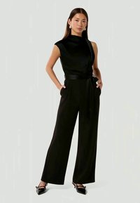 Schwarzer ärmelloser Jumpsuit mit hohem Kragen, weitem Bein-Design, taillierter Taille und einem passenden Bindegürtel. Glattes Material mit leichtem Glanz.