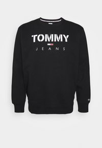 Felpa nera in cotone. Presenta "TOMMY JEANS" in grandi lettere bianche e un piccolo emblema a forma di bandiera. Collo rotondo con polsini a costine.