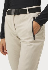 Beige gerippte Hose mit seitlichem Reißverschlussfach; schwarzer verstellbarer Gürtel mit Schnalle; glatte Stofftextur; enganliegendes Design.