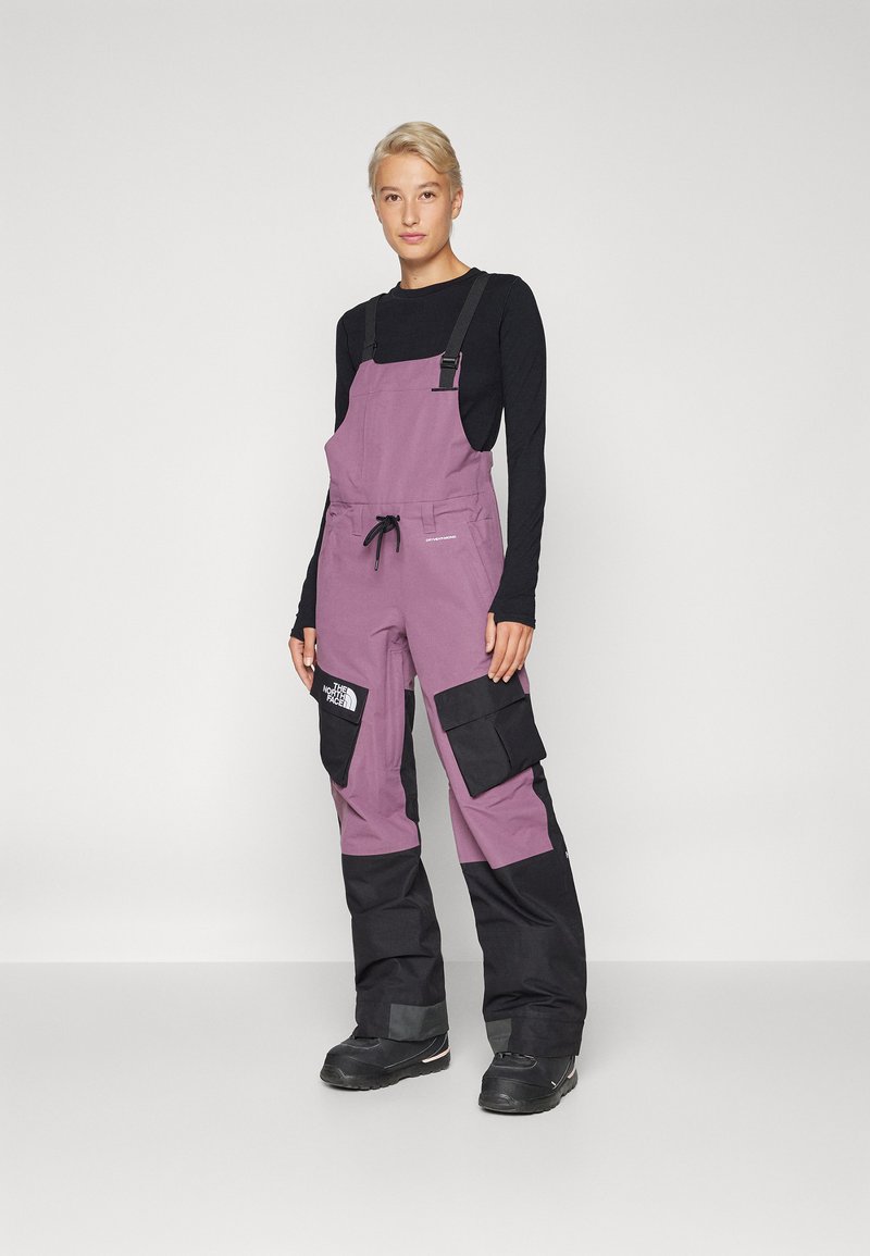 Lilla ja mustad lumeülikonnad, millel on reguleeritavad rihmad, elastne vöö ja mitmed suured taskud, valmistatud vastupidavast kangast. Sobivad külma ilma jaoks.