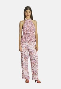 Haut à bretelles avec imprimé floral, plis et taille élastique. Pantalons floraux amples en tissu doux, avec des nuances de rose et des accents rouges.