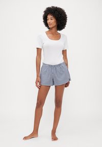 Witte korte mouw top met een vierkante halslijn, gecombineerd met marineblauwe en witte geblokte shorts. De shorts hebben een elastische tailleband.