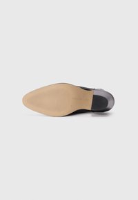 Suela de zapato negra con forma suave y redondeada. La suela de goma de color marrón claro presenta un patrón texturizado para mayor tracción. Consulte la etiqueta para las tallas.