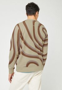 Felpa color beige chiaro con motivi arrotondati in marrone e grigio. Presenta un collo a giro e polsini a coste. La vista posteriore mostra una vestibilità morbida.