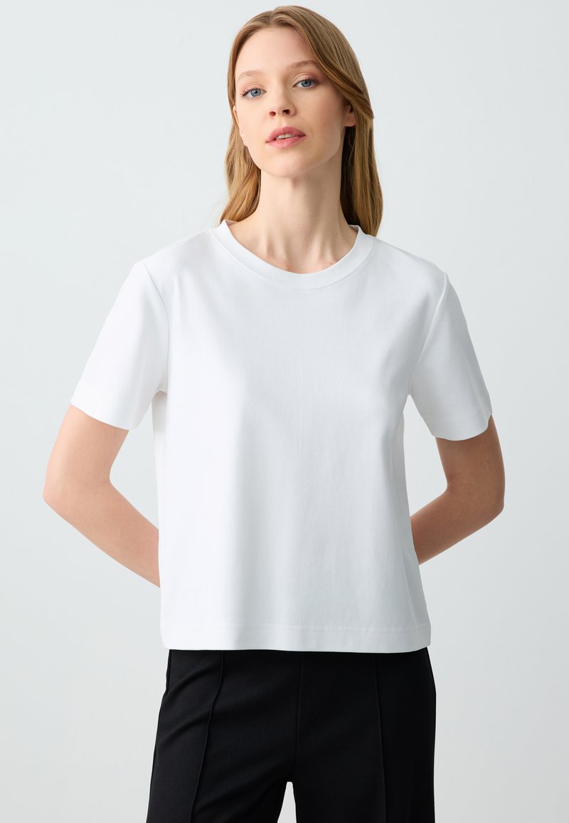 Witte T-shirt met korte mouwen, gemaakt van zachte katoen. Heeft een ronde hals en een relaxte pasvorm, met een gladde textuur en een minimaal ontwerp.