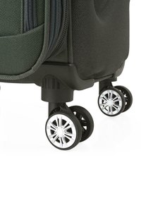 Maleta negra con superficie texturizada, que cuenta con dos ruedas plateadas brillantes y una base negra robusta para mayor estabilidad. Detalle de cremallera visible.