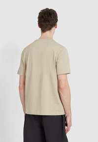 T-shirt beige a maniche corte con collo rotondo, realizzato in un tessuto testurizzato, caratterizzato da una vestibilità rilassata e un design minimale.
