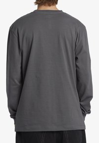 Långärmad grå skjorta i mjuk bomull, med rundad halsringning, avslappnad passform och slät yta utan synliga mönster eller logotyper.