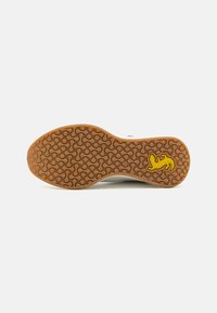 Schuhsohle, braunes Gummi mit kreisförmiger Textur, mit einem gelben Eidechsen-Logo. Der Rand ist weiß und weist auf ein kontrastierendes Design hin.
