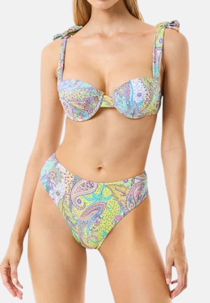 Donna che indossa un bikini con motivo paisley dai colori pastello, con slip a vita alta e spalline annodate sul top.