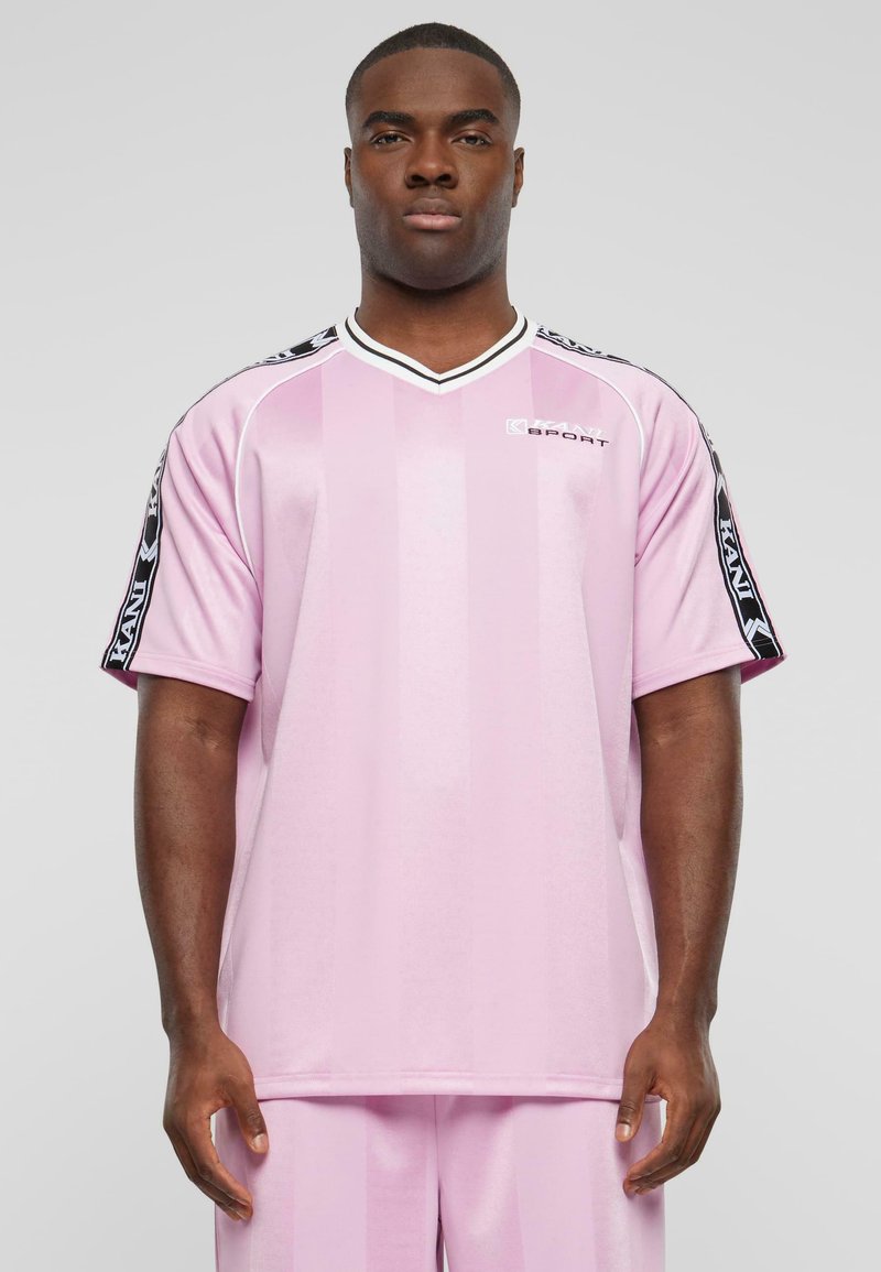 Light pink sports jersey with vertical stripes, short sleeves, and black accents on the sleeves. Features a V-neck and logo detail.