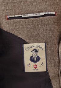 Braune Tweedjacke mit schwarzer Fütterung, Etikett mit einem Hund in Anzug und Hut, "Savile Row by Club of Gents" mit Schneider-Symbolen.