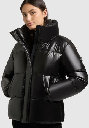 Giubbotto piumino nero con finitura lucida, colletto alto, chiusura con zip e due tasche laterali. Presenta un design trapuntato e polsini elasticizzati.