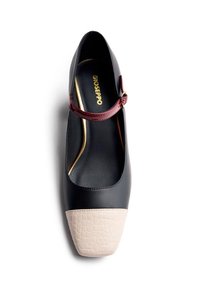 Black Mary Jane shoe with red strap and beige textured square toe, gold "Gioseppo" branding inside.