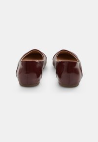 Burgunderfarbene Leder-Ballerinas mit einer abgerundeten Spitze und einer flachen Gummi-Sohle, mit einer glatten, glänzenden Oberfläche.