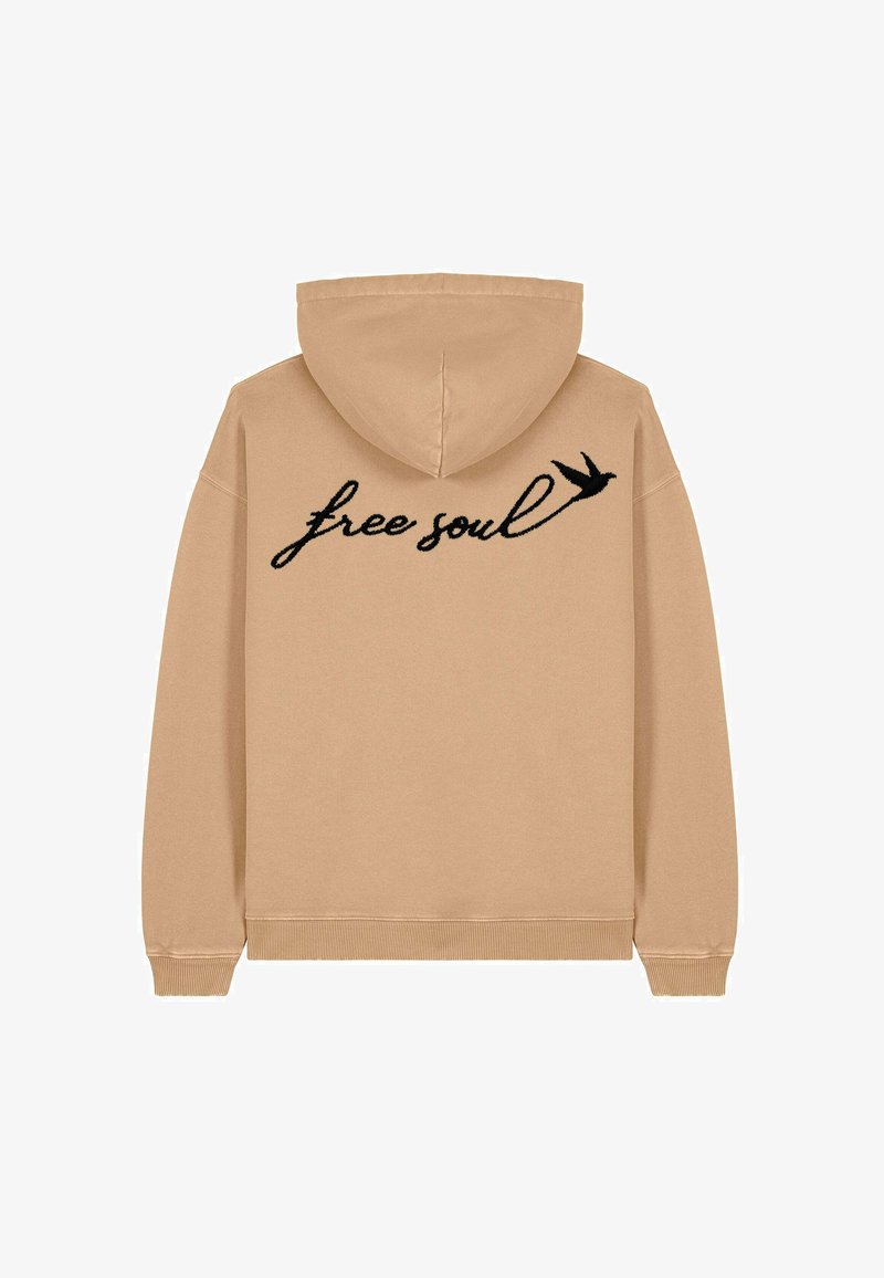 Sweat à capuche beige avec un cordon de serrage et des poignets côtelés. "Ame libre" en texte cursif noir avec un graphique d'oiseau imprimé au dos.