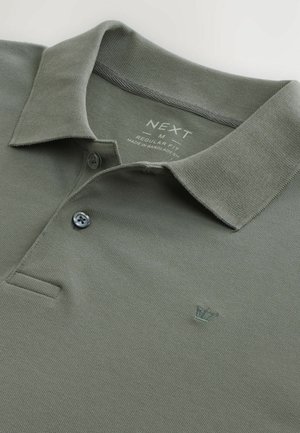 Polo shirt verde oliva realizzato in tessuto testurizzato con colletto, caratterizzato da un piccolo logo ricamato a forma di corona e chiusura con due bottoni.