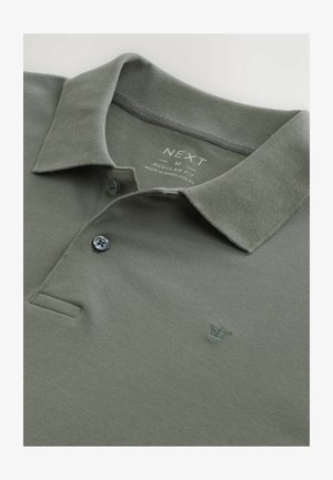 Polo olive en tissu texturé avec un col, doté d'un petit logo de couronne brodé et d'une fermeture à deux boutons.