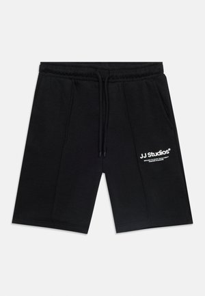 Pantalones cortos negros hasta la rodilla con cintura elástica, cordón ajustable, bolsillos laterales y logo de texto blanco "JJ Studios" en el muslo izquierdo.