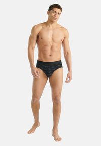 Czarne kąpielówki z teksturowanym geometrycznym wzorem, z jednolitą czarną talią i dopasowanym, opływowym krojem.