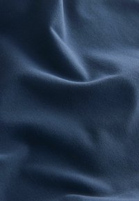 Marineblåt stof med en glat tekstur, der viser bløde folder og en subtil glans. Materialet virker let og fleksibelt.