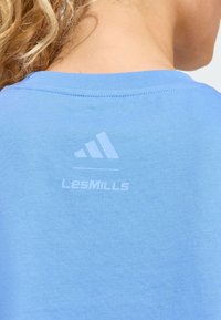 Lyseblå bomulds-T-shirt med rund halsudskæring og korte ærmer. Har et diskret hvidt logo og tekst på bagsiden nær halsen.