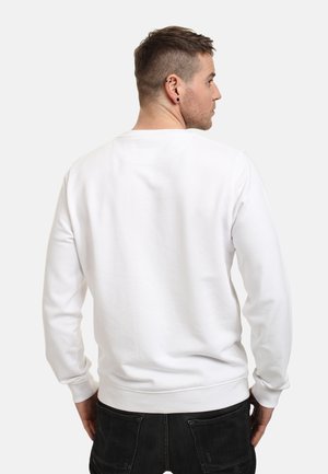 Biała bluza z długimi rękawami, okrągłym dekoltem i ściągaczami; fakturowana tkanina o gładkim wykończeniu, pokazana z tyłu.