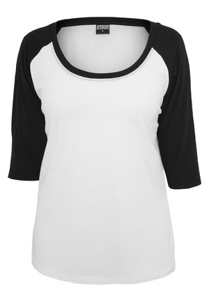 Hvid letvægts skjorte med sorte trekvart-raglanærmer og en bred rund udskæring. Har et blødt stof og enkelt design.