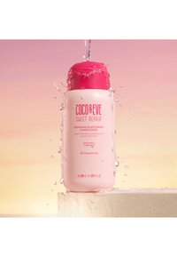 Coco & Eve Sweet Repair balsam i en glänsande rosa flaska, med ett rosa lock, vattendroppar och text som visar att det reparerar skadat hår.