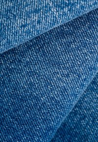 Primer plano de tela vaquera azul doblada que muestra la textura detallada y el patrón de tejido.