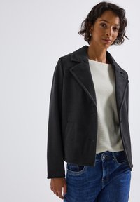 Dark gray wool-blend jacket with a notched lapel, front pockets, and a cropped design, worn over a light cream sweater.