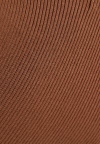 Brauner gerippter Stoff mit einer glatten Textur, der vertikale Linien aufweist und einen weichen Eindruck vermittelt, geeignet für Kleidungsstücke oder Accessoires.