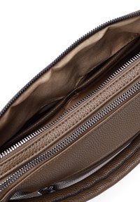 Interno della borsa in pelle marrone con texture, dotato di un compartimento con zip e rivestimento liscio. Include hardware e dettagli di cucitura in tonalità argento.