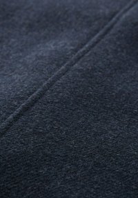 Sötétkék szövet, amelynek texturált, kissé bolyhos felülete van; jellemzője egy kiemelkedő varrásvonal, amely függőlegesen fut, jelezve a ruhadarab szerkezetét.