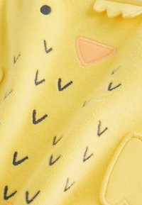 Gele fleece stof met geborduurde ontwerpen van pijlen in grijs en een snavel en oog in oranje en zwart, met een zacht gestructureerd oppervlak.