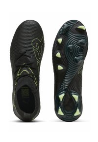 Zapatos deportivos negros con parte superior texturizada, acentos reflectantes en lima y una suela con un patrón que presenta prominentes tacos de tracción.