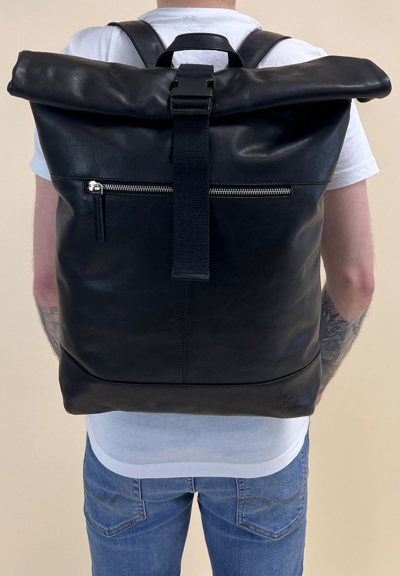Zwarte leren roll-top rugzak met een voorzak met rits, verstelbare schouderbanden en een gestructureerde afwerking. Heeft een handgreep aan de bovenkant voor eenvoudig dragen.