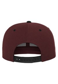 Cappello snapback bordo con visiera piatta, tessuto di cotone testurizzato, cinturino nero regolabile e fori di ventilazione sul retro.