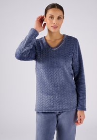 Ropa de casa suave y esponjosa de color azul, con escote en V y mangas largas. La parte superior tiene un patrón texturizado de chevrón y un sutil borde dorado en el escote.